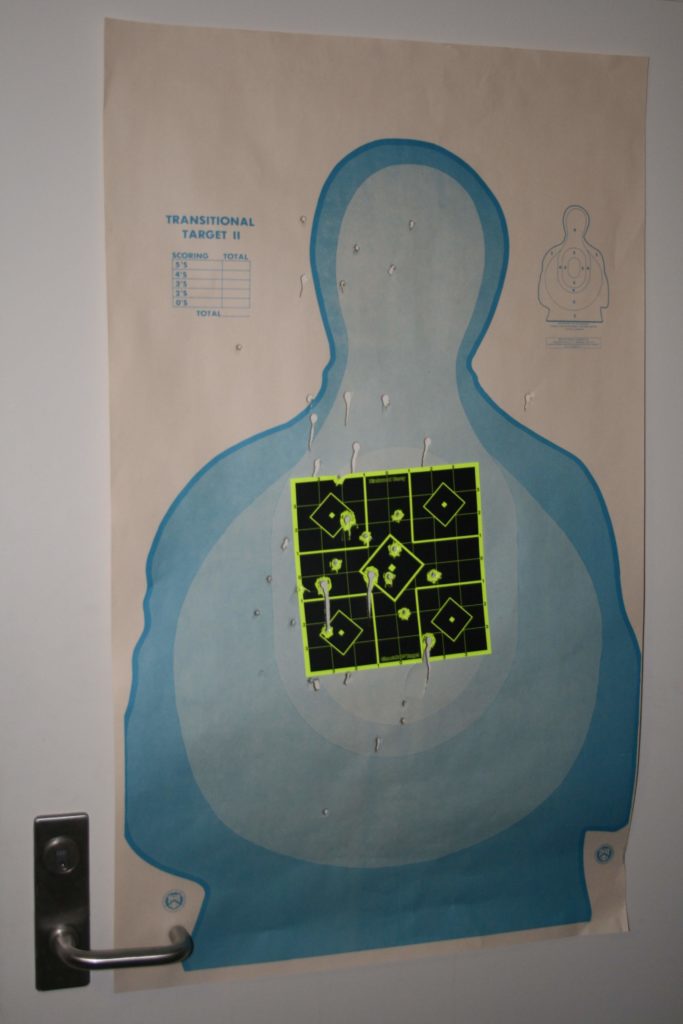A shooting range target with numerous holes.