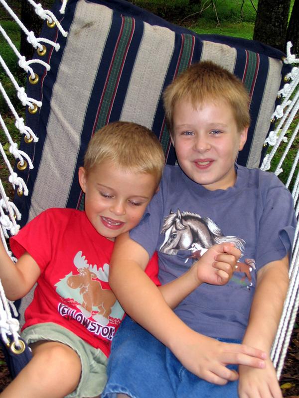 Two boys smiling in a hammock swing. 