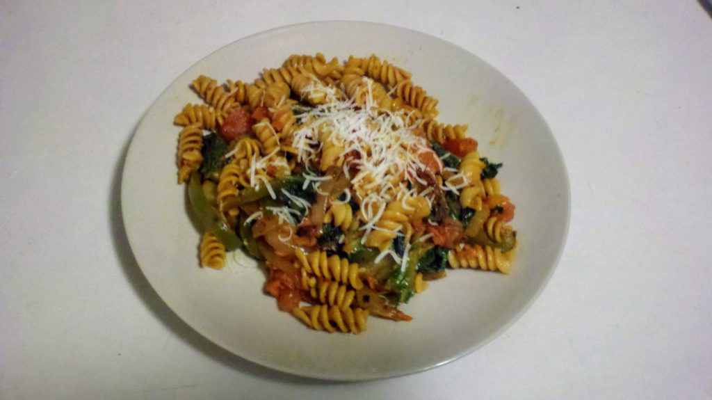 A plate of rotini pasta with a chunky vegetable sauce.